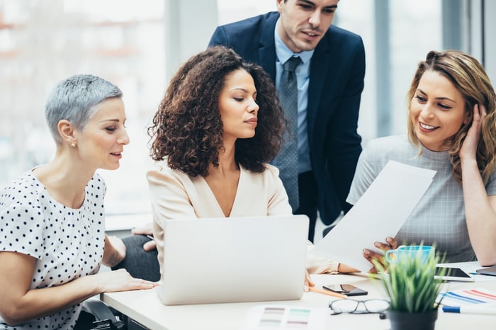 A group of investors meeting in a conference room study a document.