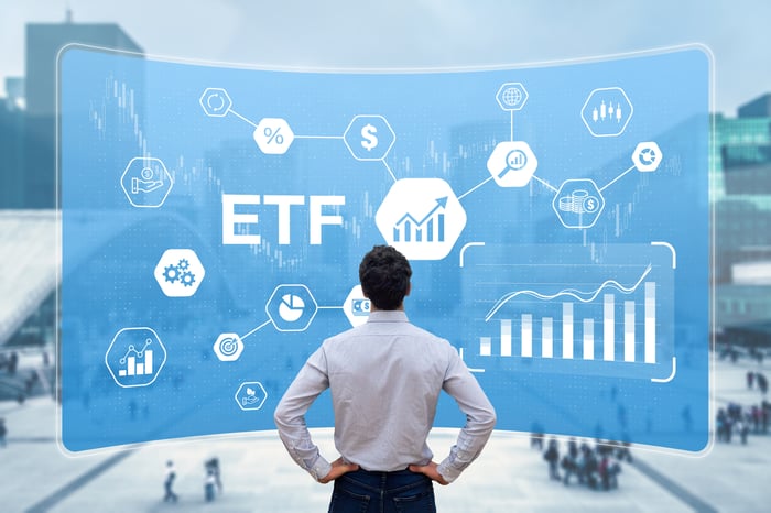 A person looking at a digital presentation of the letters "ETF" and financial-related images.