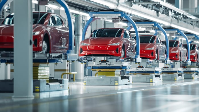 Red electric cars being assembled in a factory.
