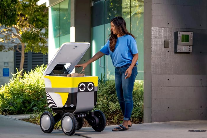 A customer accepts a delivery from a Serve Robotics robot. 