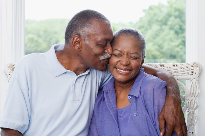 Two people hugging while one kisses the other on the cheek.