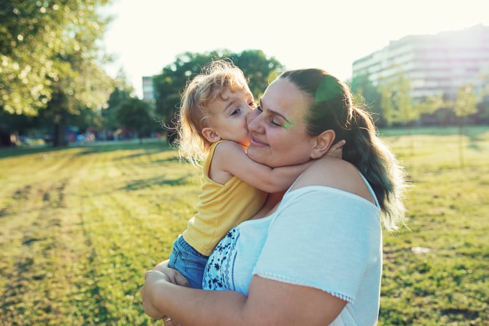 A child holding an adult while they kiss them on the cheek.