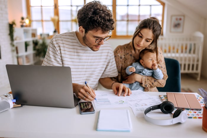 A couple with a baby sit at a computer.