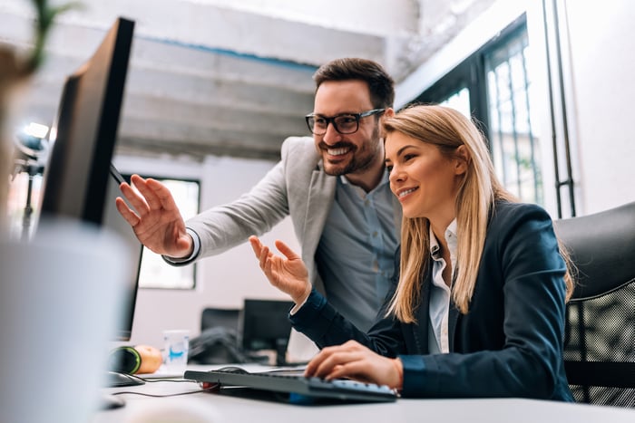 Two pleased investors in an office look at something on a computer screen.