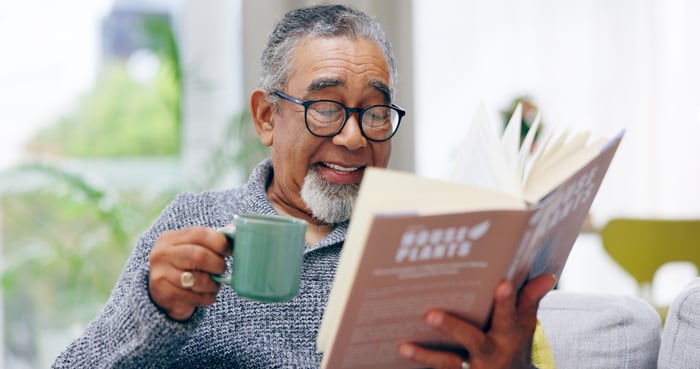 Someone is holding a mug and an open book, while smiling.