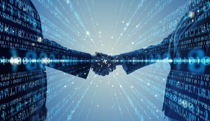 Rendering of two people wearing professional attire shaking hands with binary code emitting in different directions out and away from the handshake.