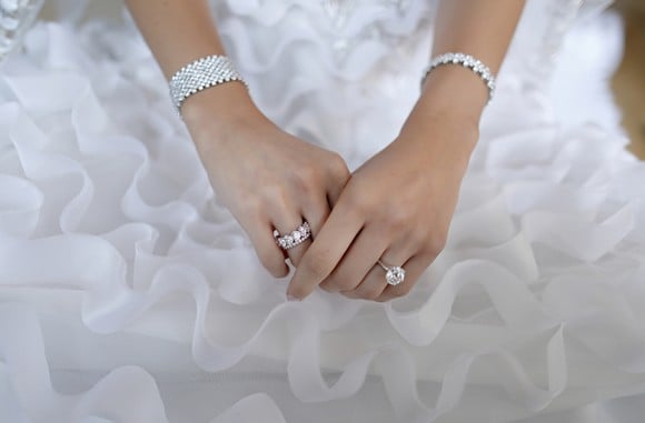 A bride's hands with jewelry on them.