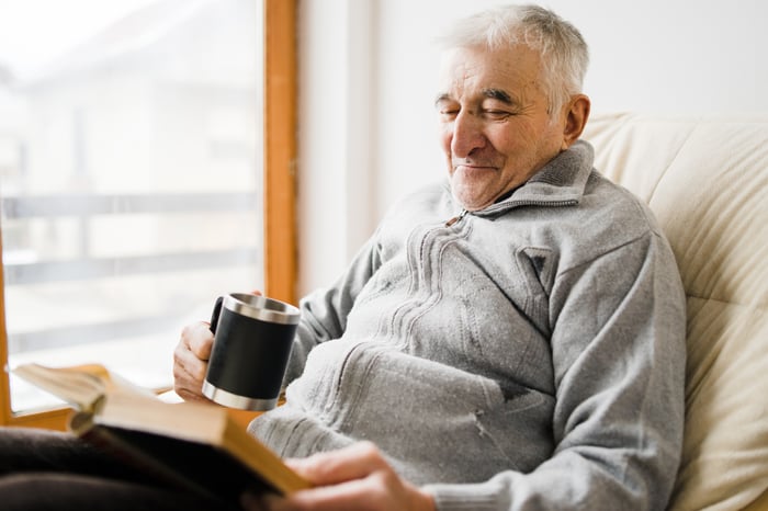 Someone reading a book with a coffee mug in one hand.