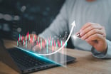 person on a laptop with a virtual concept of stock data going upward getty