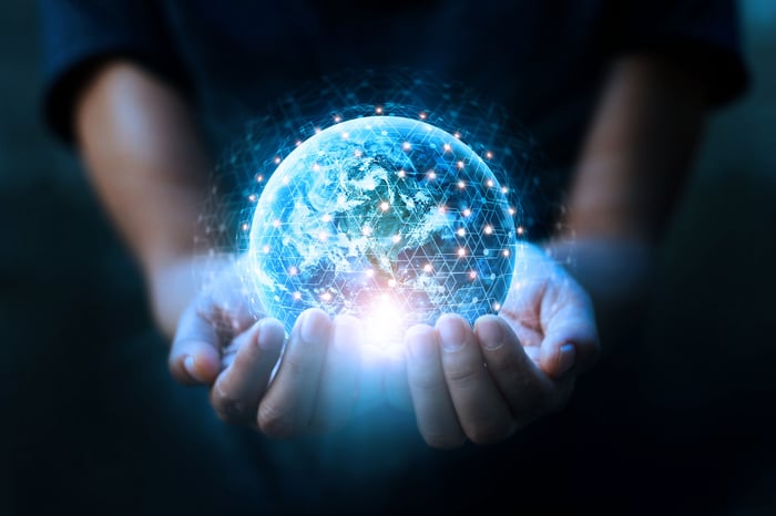 Cupped hands hold a glowing Earth globe surrounded by white nodes representing internet satellites.