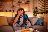 Man looks upset while sitting on a couch.