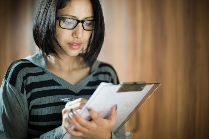 An investor takes notes on a clipboard.