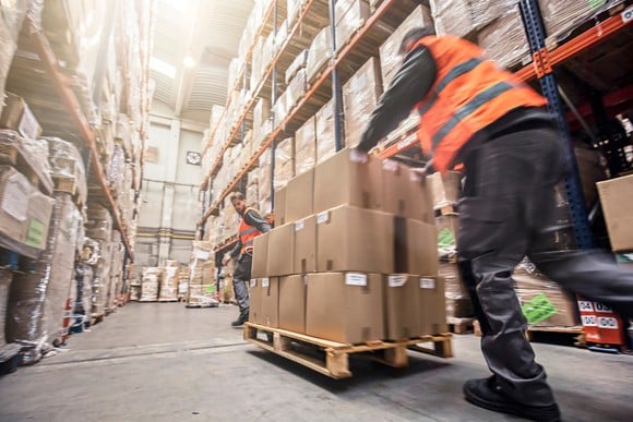A person moving boxes in a warehouse.