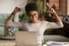 A woman raising her arms in triumph in front of a computer