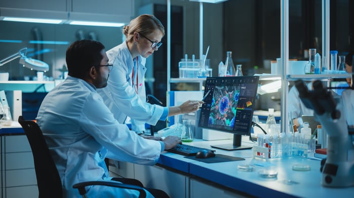 Two people in a clinical laboratory setting using a computing device.