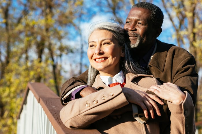 Smiling couple standing on steps looking out at nature.