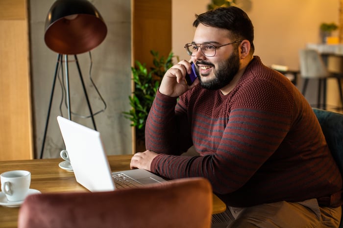 An investor smiles while talking on the phone.