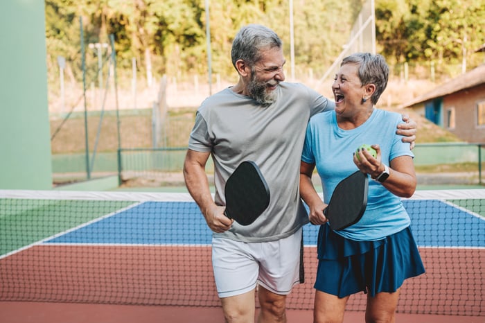 Two people hugging while holding pickleball rackets.