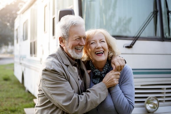 Two people hugging in front of a recreational vehicle.