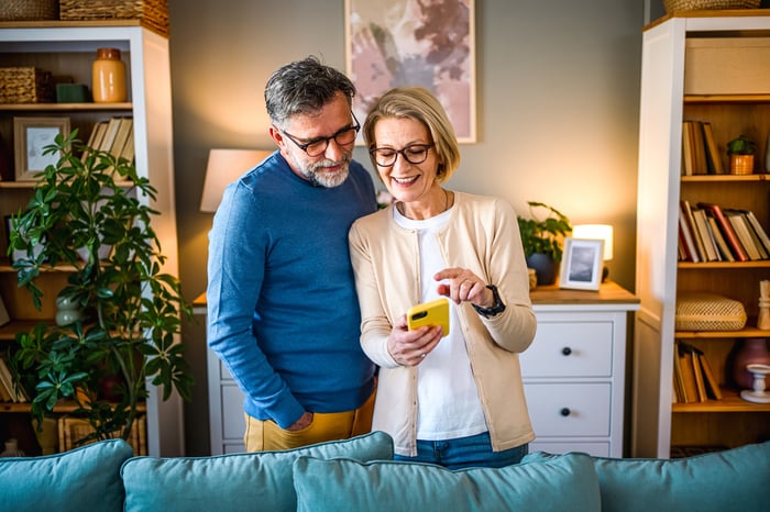 Two people in a living room setting reacting to content on a handheld mobile device. 