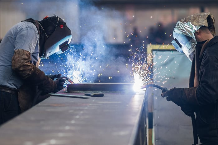 Two people welding in a factory.