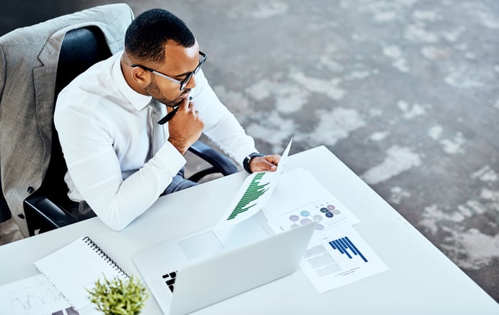 Person at desk, analyzing charts and data.