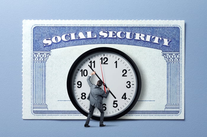 Social Security card behind a person moving the hands on a large clock.