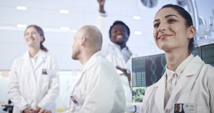 Researchers smile while working in a lab. 