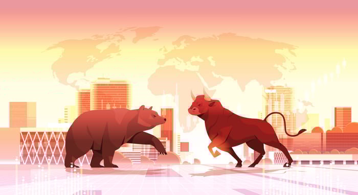 A graphic of a bull facing a bear with a skyline and world map in the background.