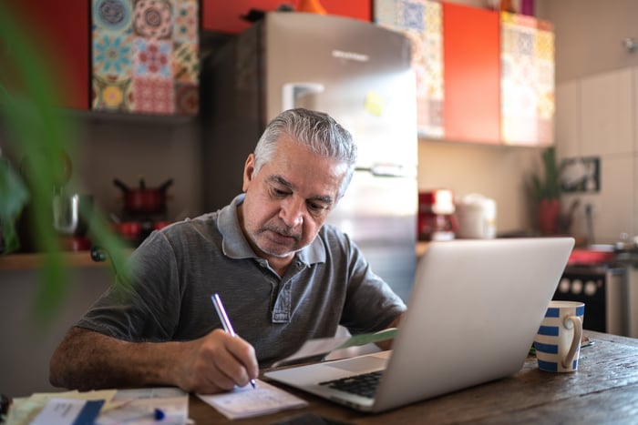 Person sitting in front of laptop writing note.