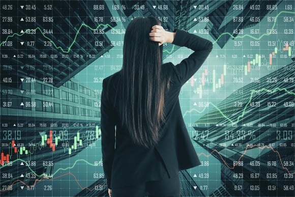 A person looks at a stock chart with their hand on their head.