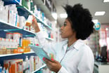 Person checking medicine on a shelf in a pharmacy
