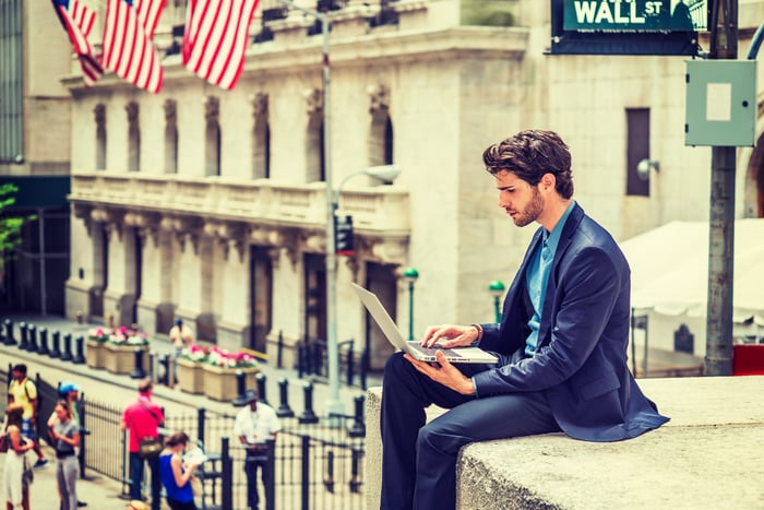 Investor with laptop on Wall Street.