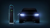 Electric car with headlights glowing and plugged into a charging station.