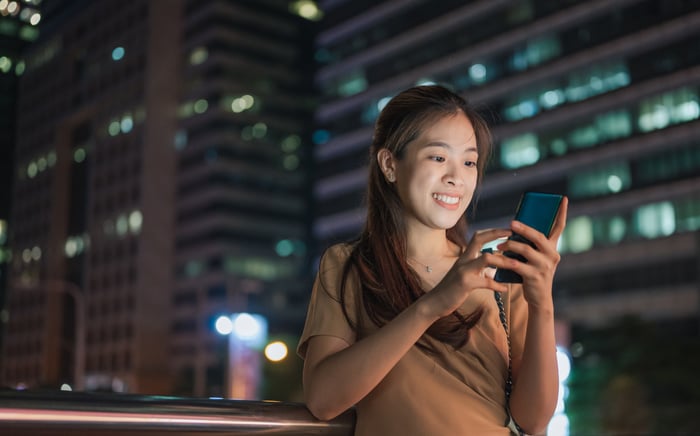 Investor standing outside with mobile phone at night.