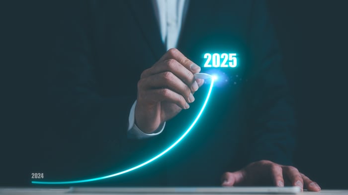 A person in business attire drawing an arrow with an upward trajectory marked 2025.