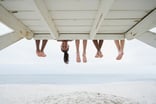 People's legs sticking out from under a boardwalk with one face