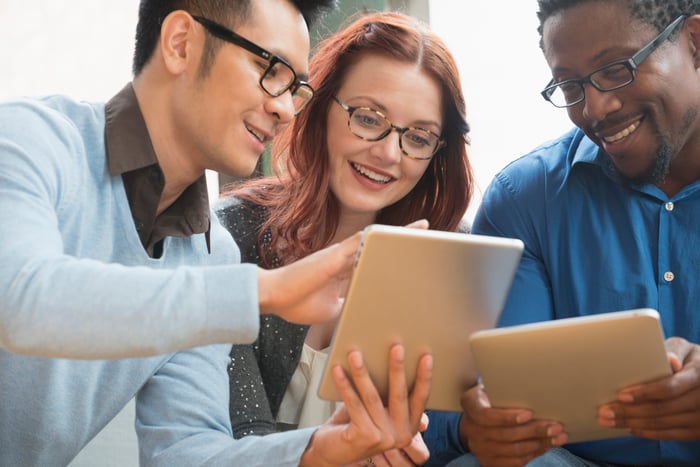 Three investors gather around a tablet.