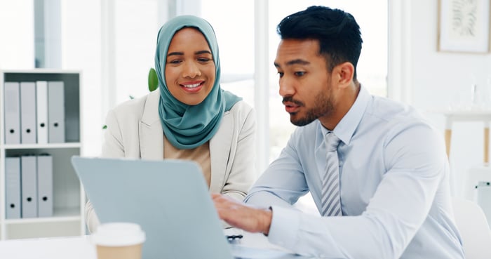 Two people working together on a laptop computer.