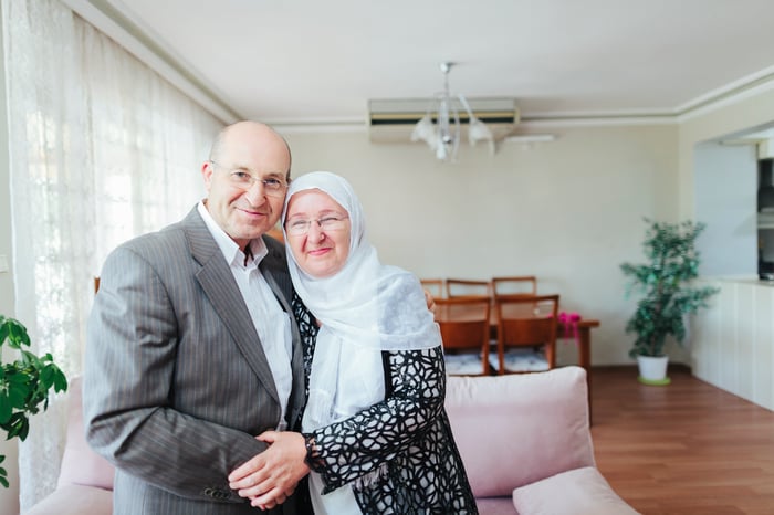 A couple is holding hands and smiling indoors.