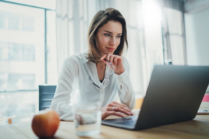 An investor studies something on a laptop in an office.