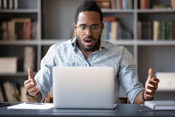 A person looking at a computer screen with a look of unpleasant surprise.