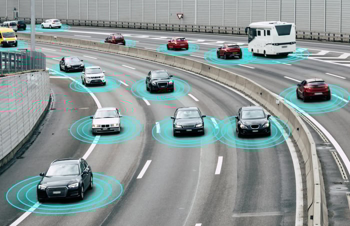 Vehicles driving on the highway with a concept showing sensors around the vehicles.