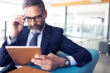 investor in business attire reviews information on a tablet