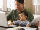 A person sitting with their child looking at a laptop.