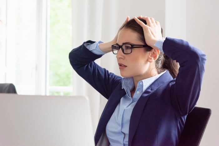 Businesswoman cringes at her laptop screen.