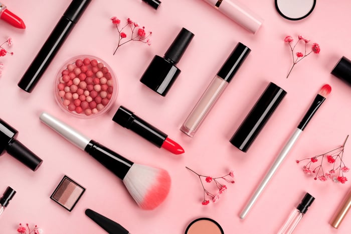 Assortment of cosmetics with red and pink colors laid out on a flat surface.