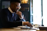 affluent young person smiles reads computer