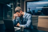Frustrated person sitting next to a laptop.
