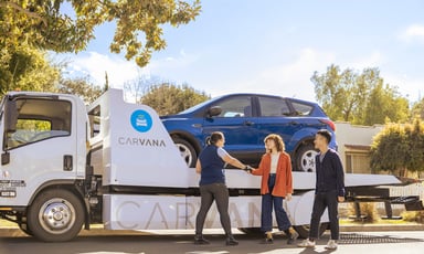 person greeting delivery driver with _carvana delivery truck and logo in background_carvana_
